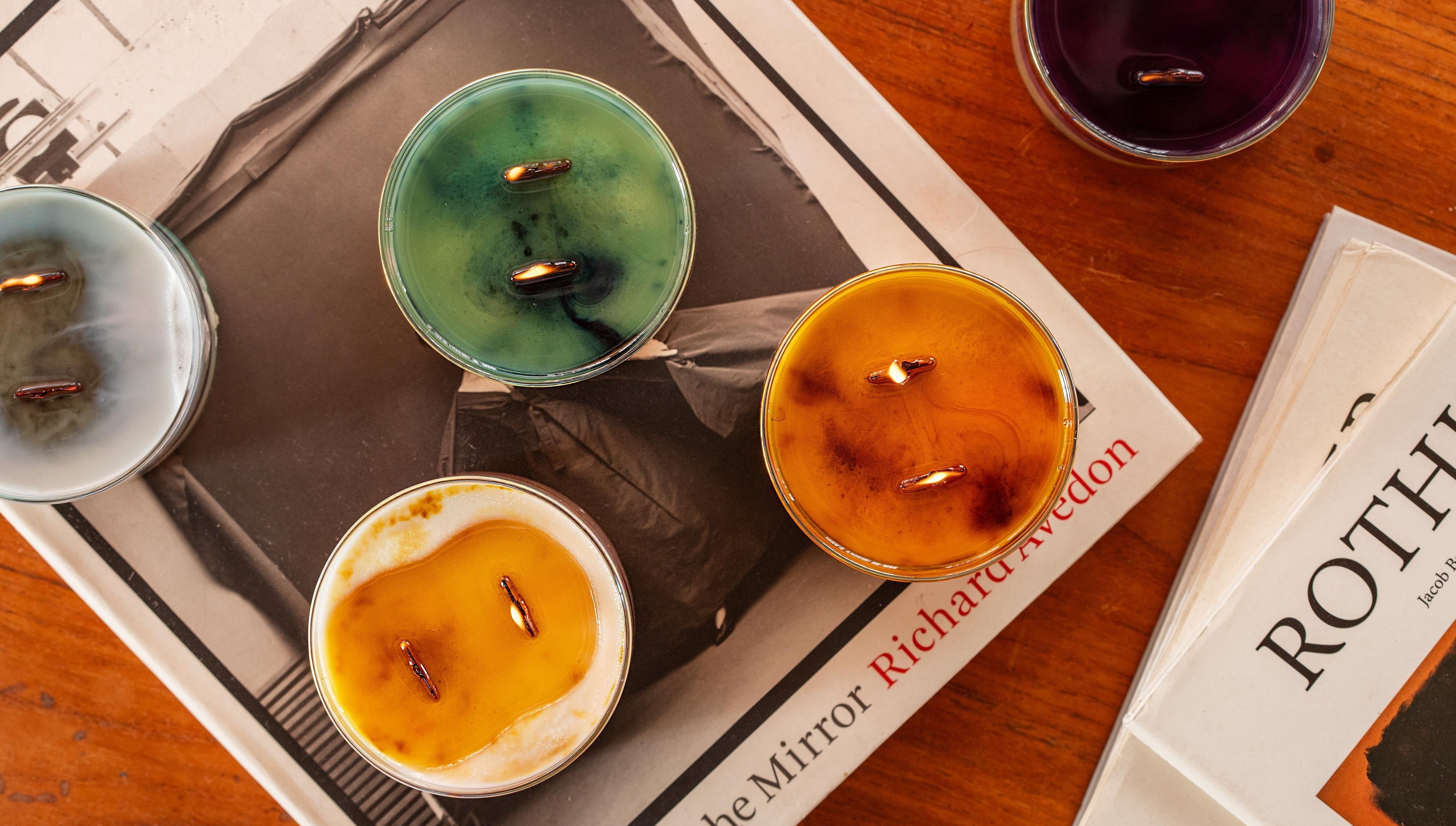Three small candles with different colored wax on a magazine