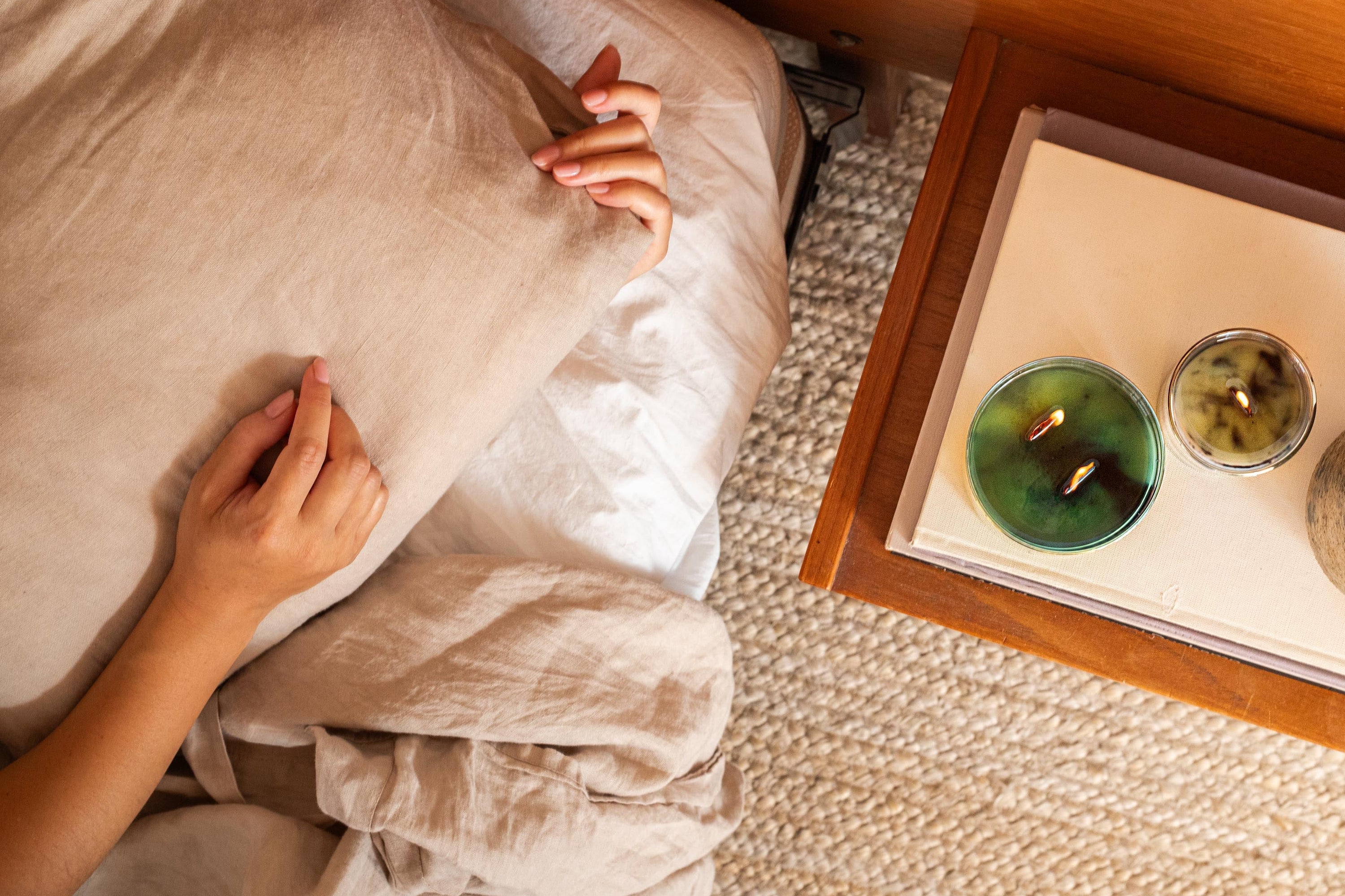 Person lying on a bed with candles on a nightstand